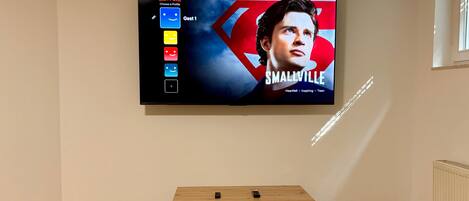 A television mounted on a wall displaying a movie poster for 'Smallville.'