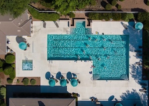 Vue aérienne d’un espace piscine comprenant plusieurs couloirs de nage, des chaises longues et des parasols.