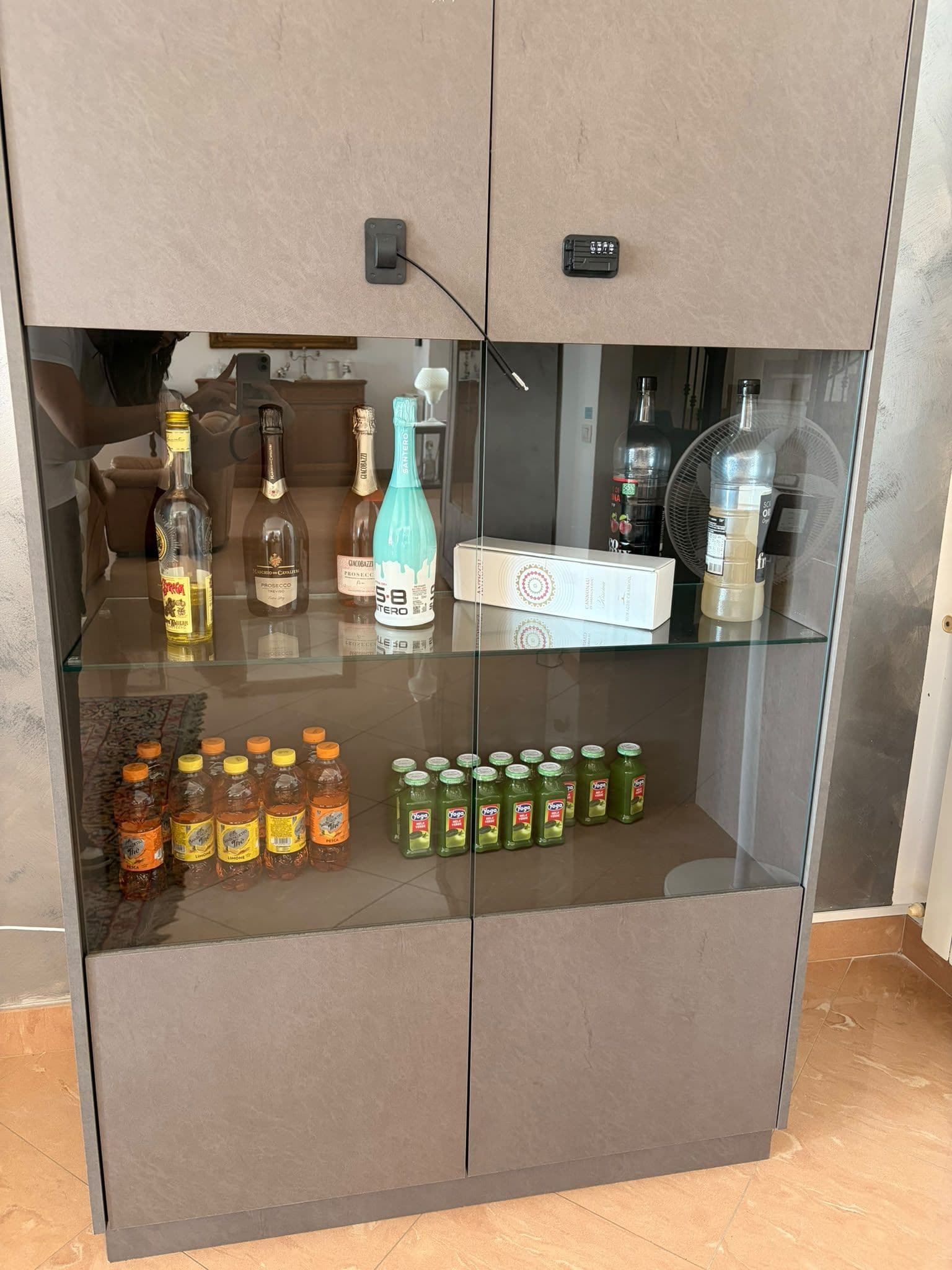 Eine Minibar mit verschiedenen Getränken, darunter alkoholische Flaschen und Saft.