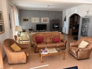 A living room with a brown leather sofa set, a coffee table with chess pieces, and a television.