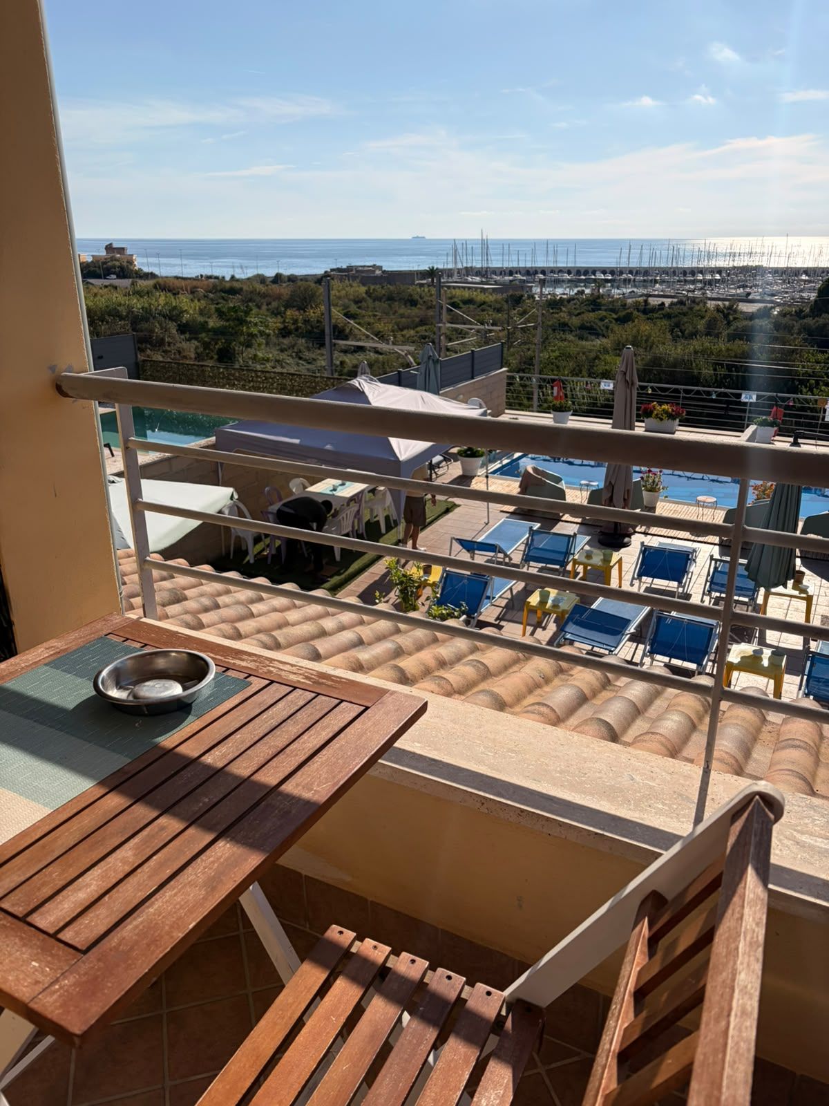Un balcone con vista su una zona piscina, un tavolo da pranzo e una ciotola di metallo.