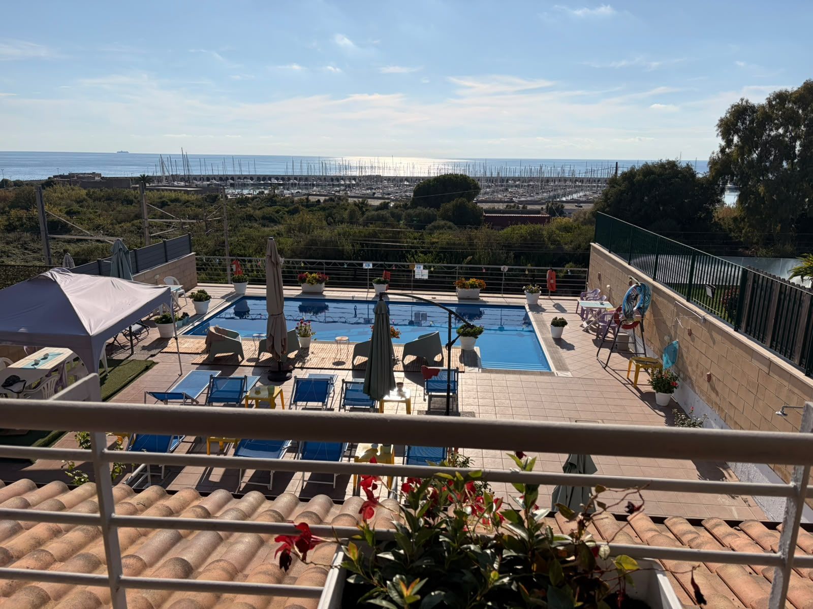 A rooftop pool area with lounge chairs and a view of the sea.
