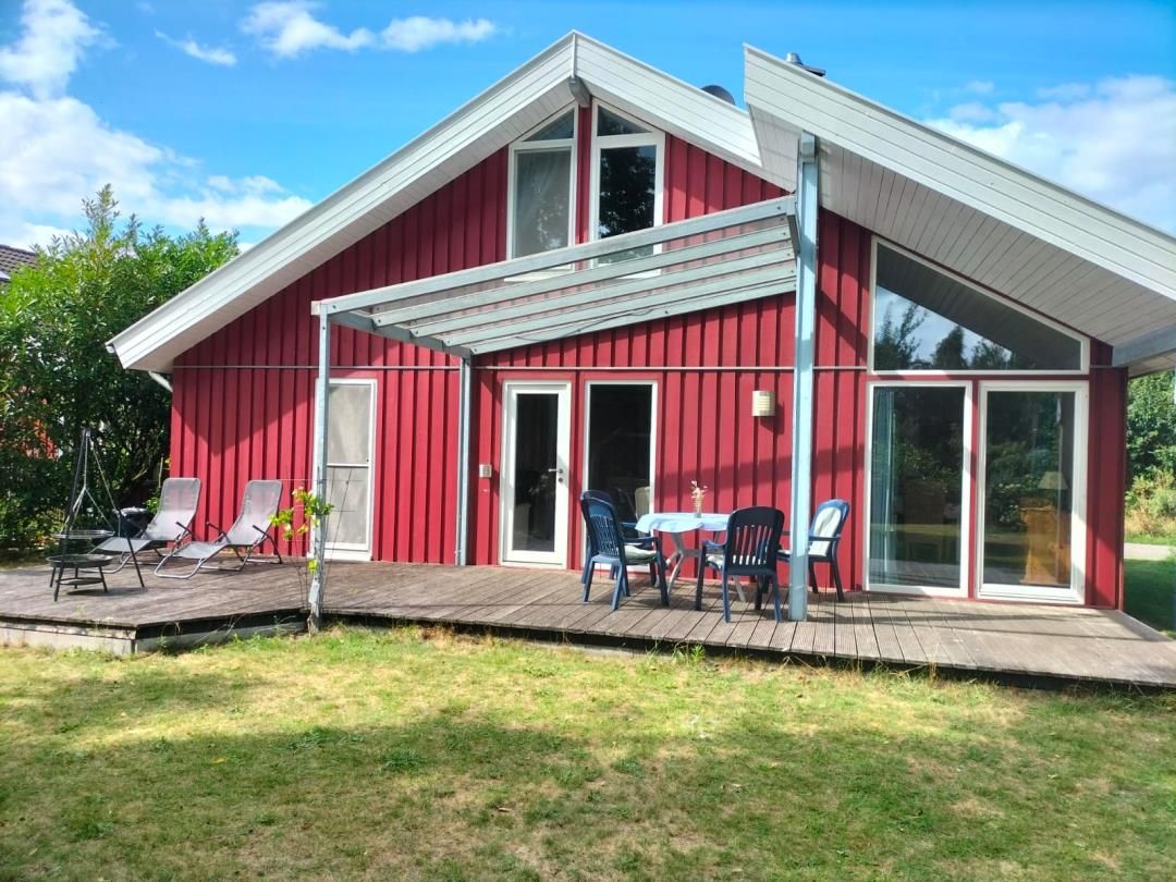 A red building with a covered patio, outdoor seating, and large windows.