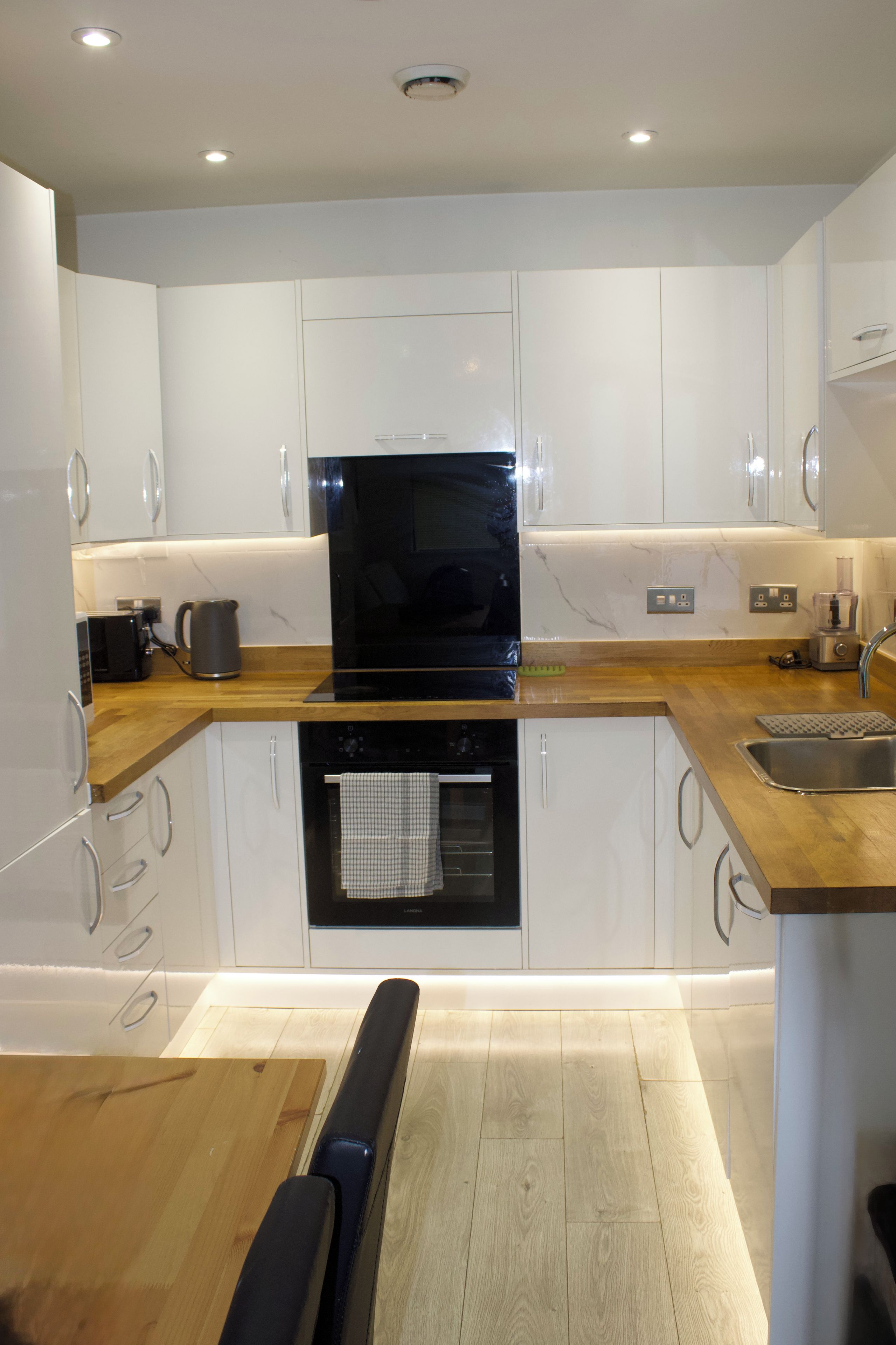 Una cocina moderna con armarios blancos, un horno negro y una encimera de madera.