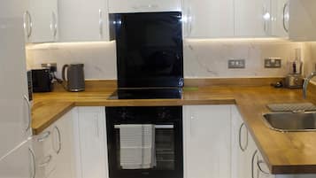 Una cocina moderna con armarios blancos, un horno negro y una encimera de madera.