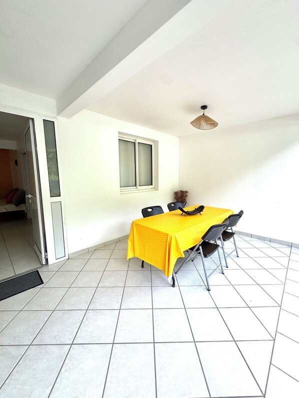 A dining area with a yellow tablecloth, four chairs, a window, and a ceiling fan.