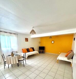 A living room with a dining table, chairs, a sofa, and a TV.