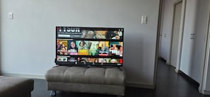 A flat-screen TV mounted on a wall with a selection of streaming content displayed. - Room-cozy Apartment Rental in Germiston (Germiston)