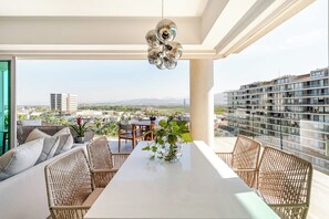 Uma varanda com móveis de vime, uma mesa e um lustre.