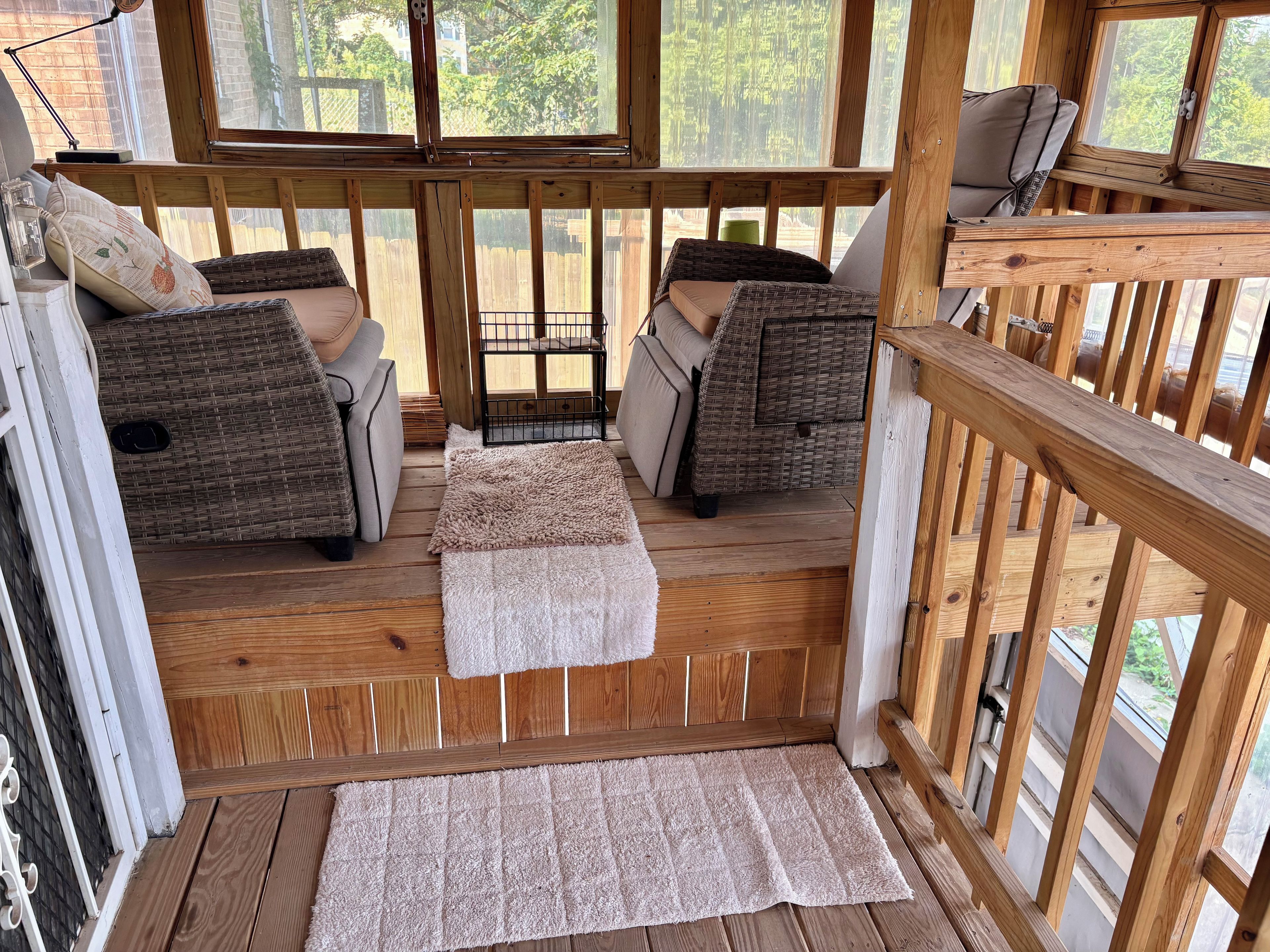 A wooden deck with two wicker sofas and a small table, surrounded by a wooden railing.