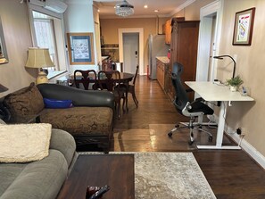 A living room with a sofa, a coffee table, and a dining area with chairs and a table. - Cozy Home in SE Washington, DC (Washington)