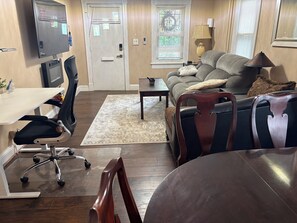 Un salon comprenant un canapé, une table basse, un téléviseur et un bureau avec une chaise.