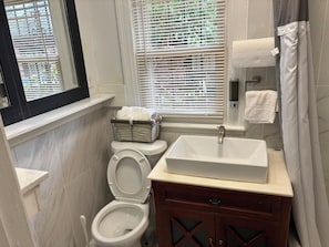 A compact bathroom with a toilet, sink, and window with blinds. - Cozy Home in SE Washington, DC (Washington)