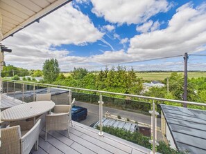 A balcony with wicker furniture and a view of a road and greenery. - Steepholm House | Scenic View | Parking | Sleeps 8 (Worcestershire)