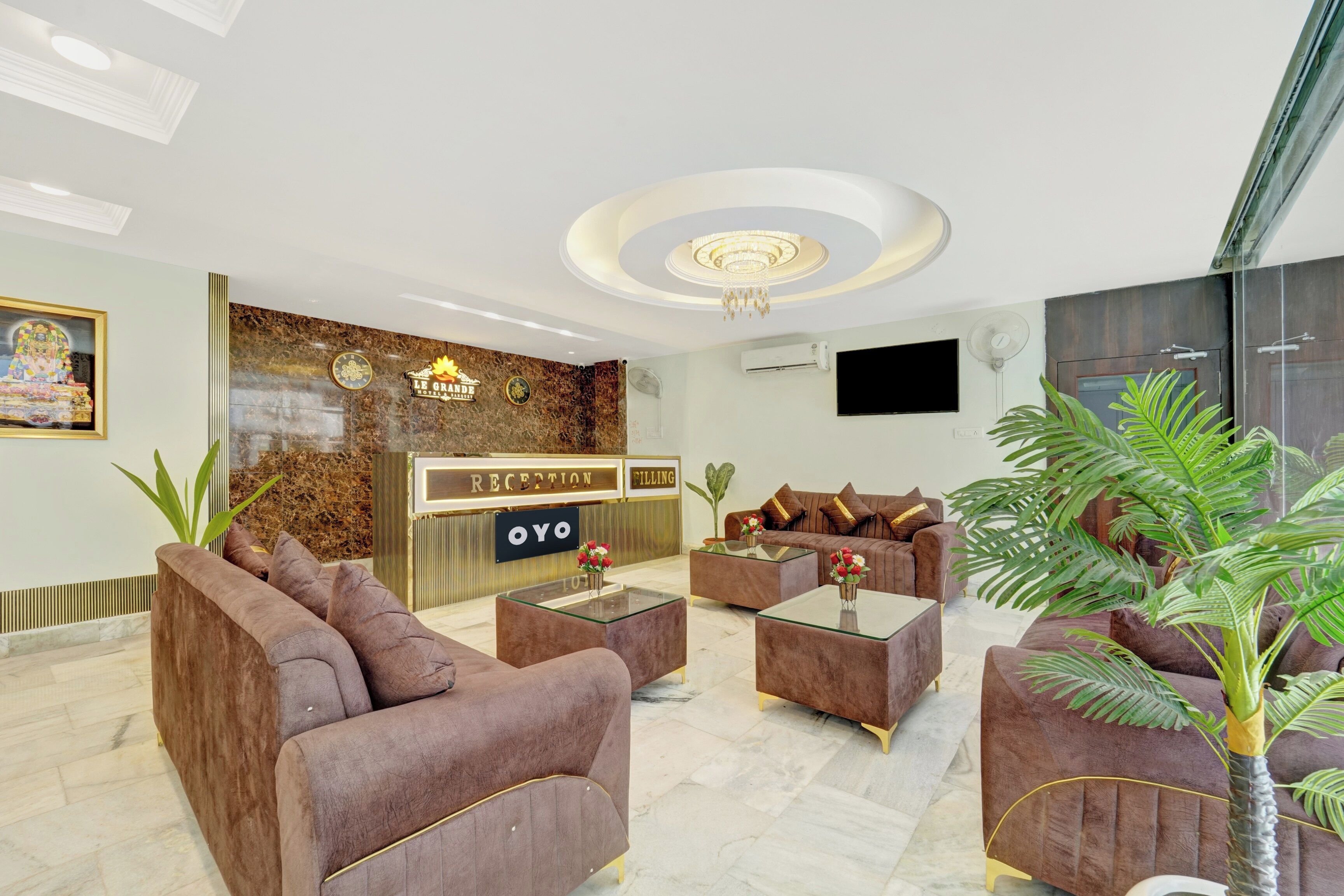 Un hall d’hôtel avec un comptoir de réception en marbre, des fauteuils confortables et un lustre.
