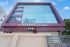 Ein modernes Hotelgebäude mit Glasfassade und Beschilderung für Le Grande Hotel & Banquet.