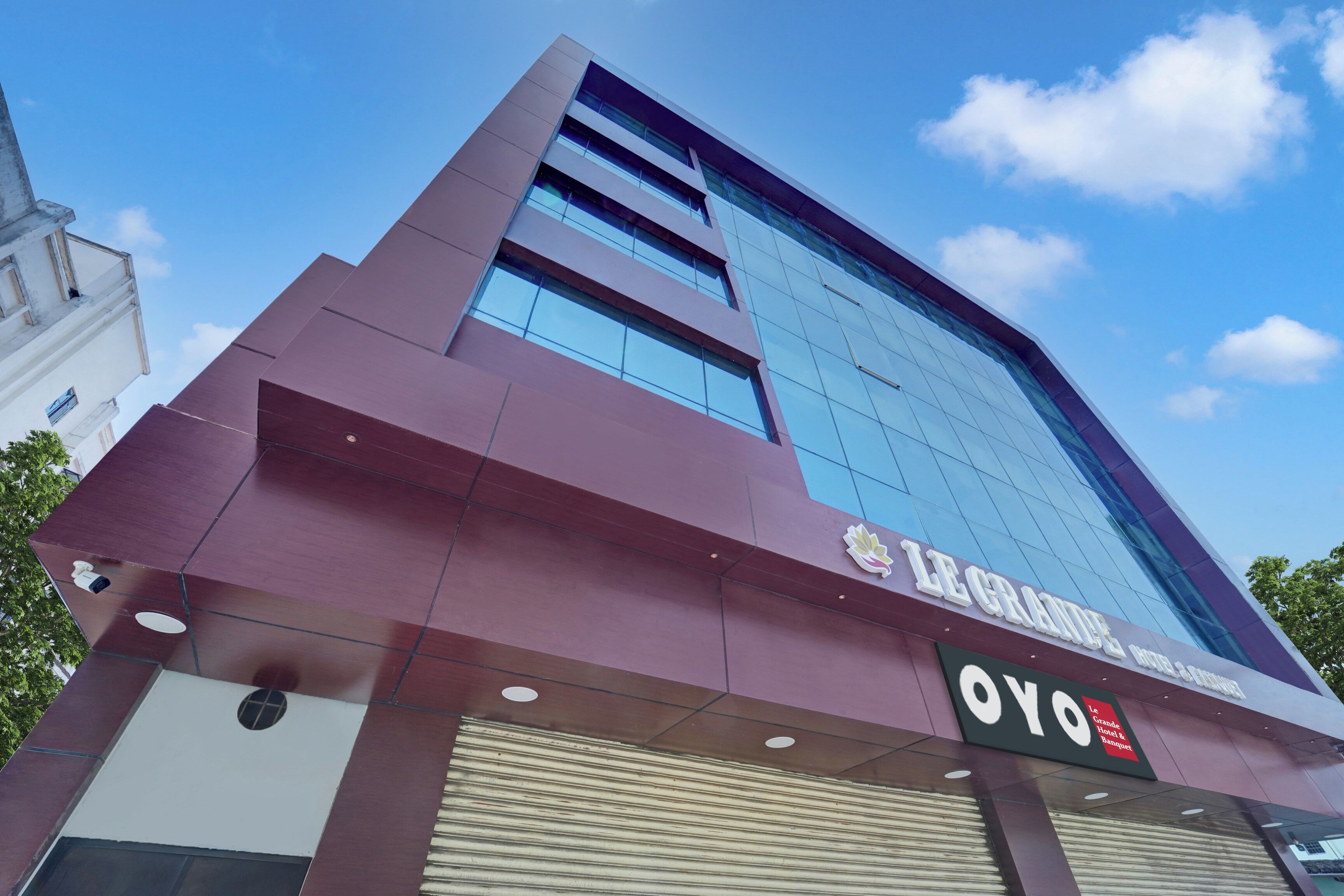 A modern hotel building with a prominent sign for 'Le Grande Hotel & Banquet' and a 'YO' logo.