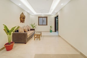 A modern living room with a sofa, a coffee table, and potted plants. - Hotel O Le Grande Hotel & Banquet (Patna)