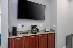 Eine moderne Küche mit Flachbildfernseher an einer Granitarbeitsplatte, einer Kaffeemaschine und einem Schild mit der Aufschrift 'COFFEE TIME'.