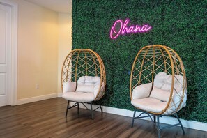 Two wicker chairs with cushions against a wall with a green textured backdrop and a neon sign that reads 'Ohana'. - Spacious 11-bedroom house in tranquil Kissimmee with AC (Kissimmee)