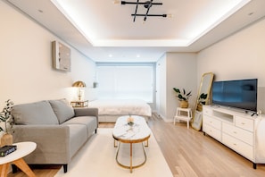 A modern living room with a sofa, coffee table, TV, and a large window. - Welcome to Your Home in the Heart of Seoul! (Jongno-gu)