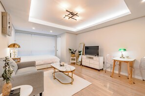 A modern living room with a sofa, coffee table, TV, and a dining area with a table and chairs. - Welcome to Your Home in the Heart of Seoul! (Jongno-gu)