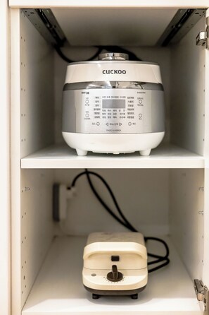 A white electrical device with a control panel on top, placed inside a white cabinet with a shelf below. - Welcome to Your Home in the Heart of Seoul! (Jongno-gu)