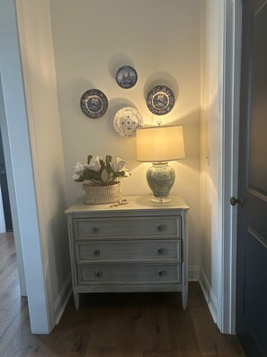 Eine Ecke mit einem weißen Schminktisch, einer Lampe und drei dekorativen Tellern an der Wand.