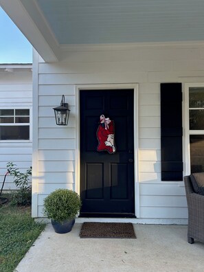 A house with a black front door, a small porch, a potted plant, and a wicker chair. - Charming 3 bedroom home in Oxford. Located 3.3 miles from the Square and Grove. (Oxford)