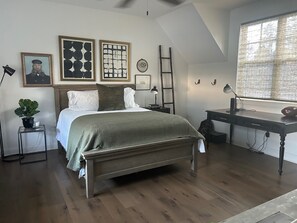 A bedroom with a bed, bedside tables, a desk, and a window with blinds. - Charming 3 bedroom home in Oxford. Located 3.3 miles from the Square and Grove. (Oxford)