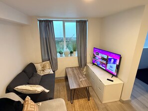 A modern living room with a sofa, a coffee table, and a flat-screen TV.