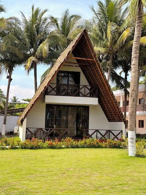 A two-story house with a thatched roof, surrounded by palm trees and a well-maintained lawn. - Hotel El Marinero (Chiquimulilla)
