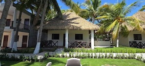 Un resort con estructuras de techo de paja, palmeras y un césped cuidado.