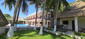 A resort with a pool, palm trees, and a thatched-roof building. - Hotel El Marinero (Chiquimulilla)