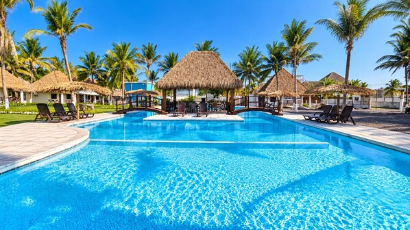 A swimming pool with lounge chairs and thatched-roof structures.