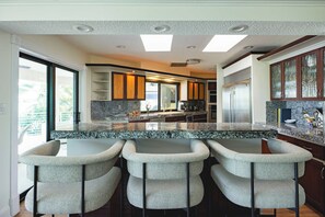 A modern kitchen with a granite countertop, bar stools, and a large refrigerator. - Kokomo Keys - Waterfront & Heated Pool (Key West)