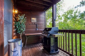 A covered outdoor area with a grill, a bench, and a trash can. - Cabin in Pigeon Forge - Welcome to Lucky Logs! (Pigeon Forge)