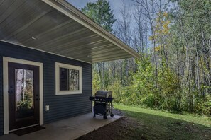 A house with a covered porch, a grill, and a door with a window. - Beautiful cozy 2-bedroom cottage with a woodburning stove and AC in Duluth (Duluth)