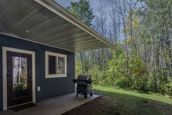 A house with a covered porch, a grill, and a door with a window.