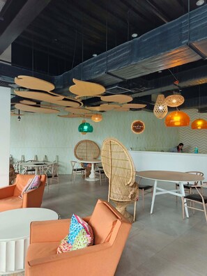 Un intérieur moderne comprenant un comptoir d’accueil, un espace salon et des luminaires suspendus.
