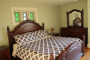 Une chambre à coucher avec un lit en bois, une table de chevet, une commode et un miroir.