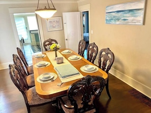 Une salle à manger avec une table en bois dressée pour huit personnes, entourée de chaises rembourrées.