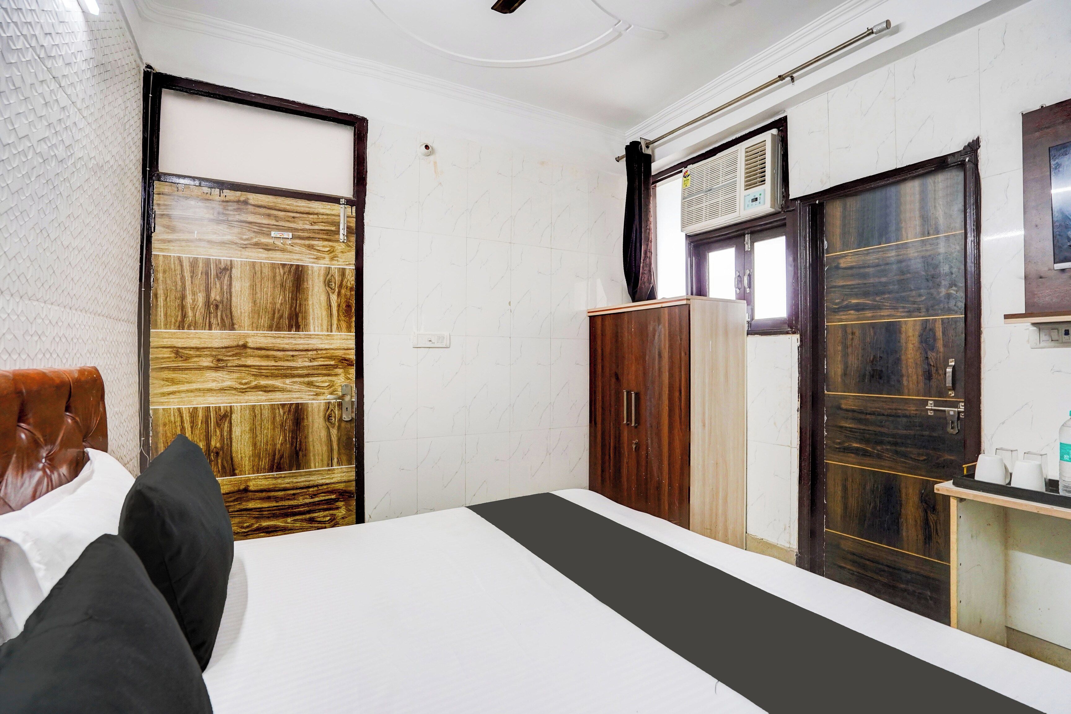 Una habitación de hotel con cama, armario, escritorio y silla, y una ventana.