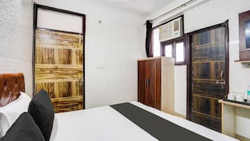 Una habitación de hotel con cama, armario, escritorio y silla, y una ventana.