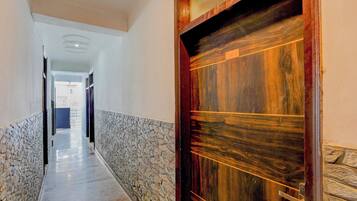 Un pasillo con una pared de piedra a un lado y una puerta de madera al otro.