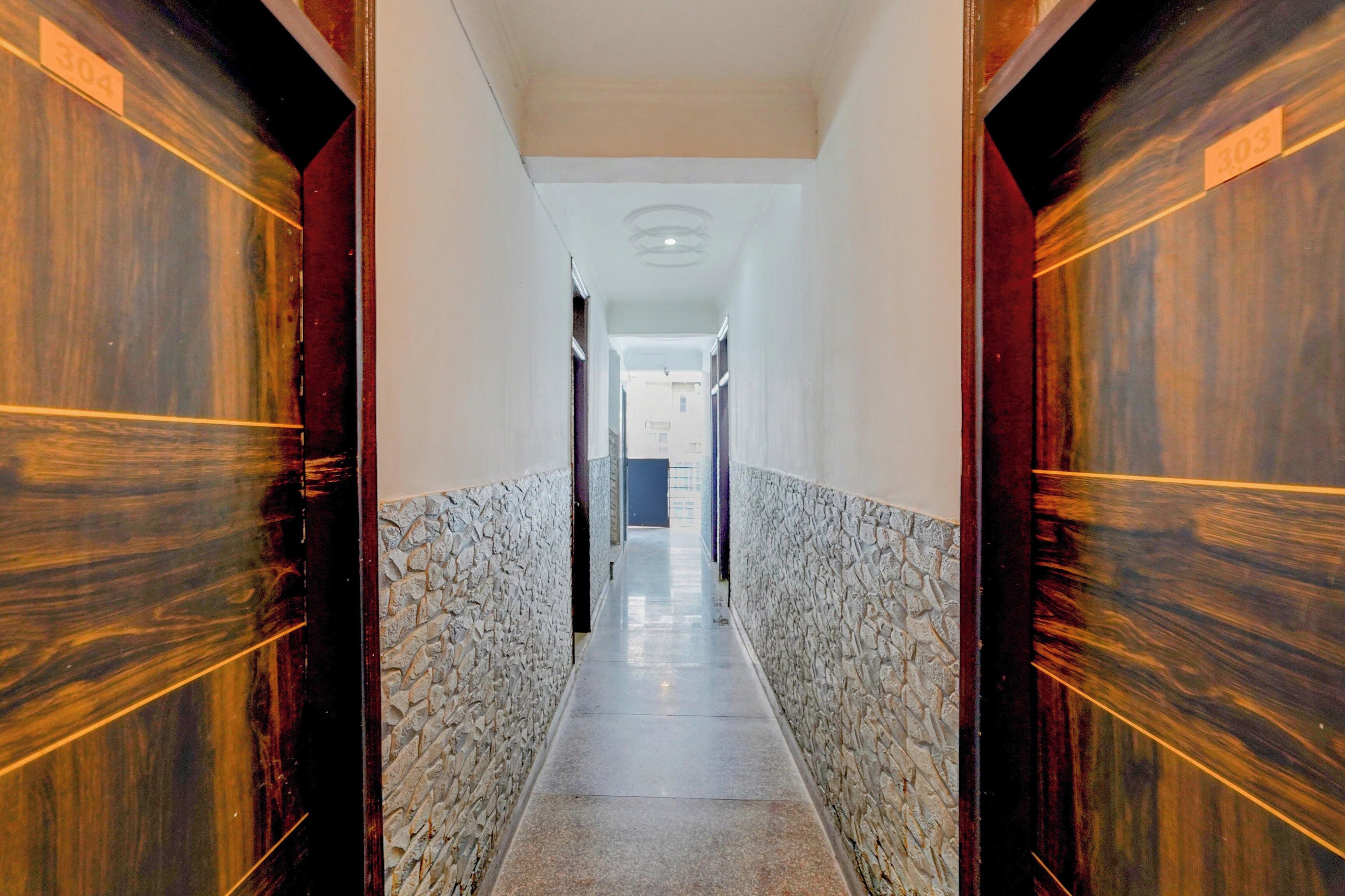 Un pasillo con pared de piedra, puertas de madera y suelo de baldosas.