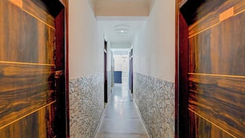 Un pasillo con pared de piedra, puertas de madera y suelo de baldosas.