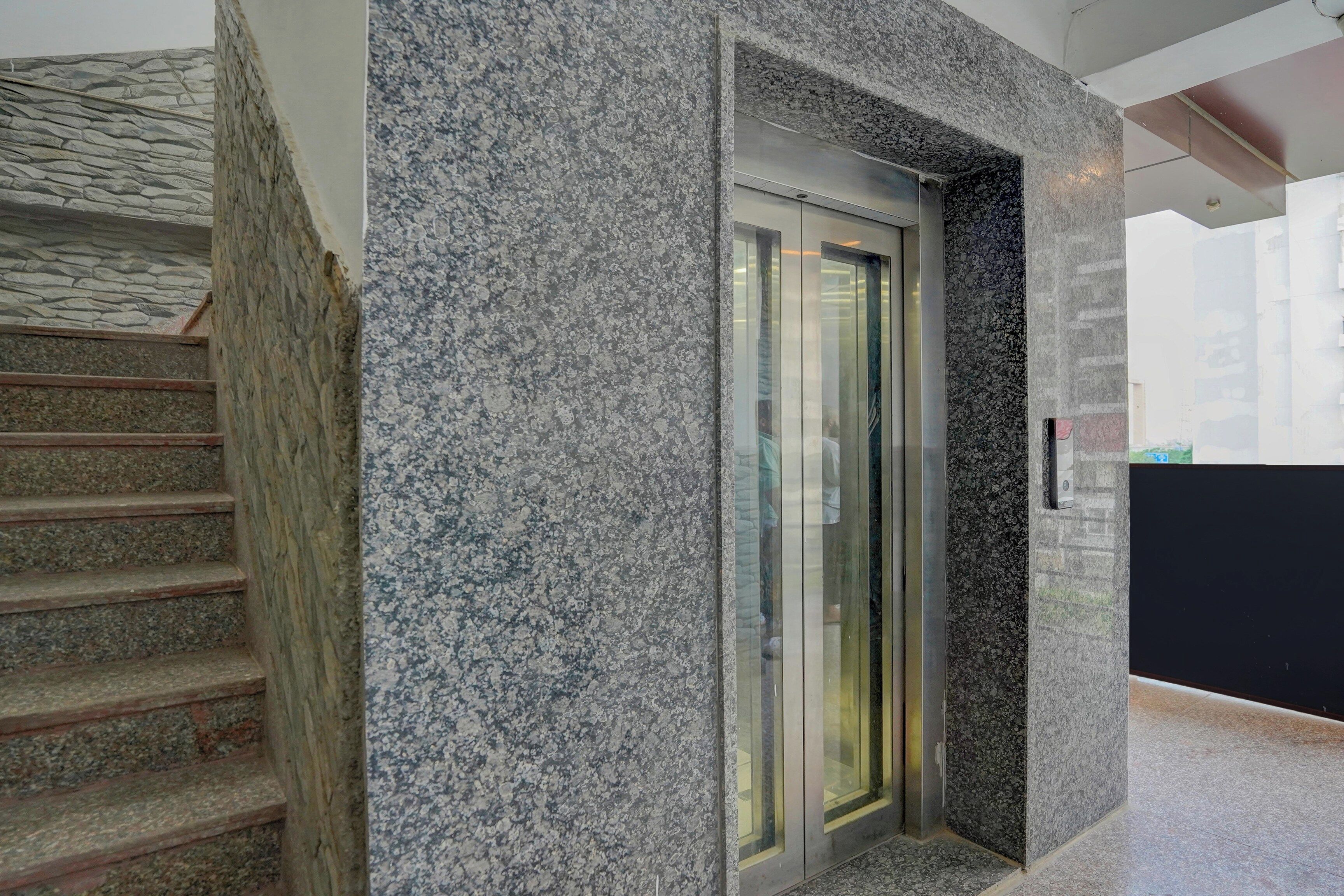 A staircase with stone steps leading to a modern elevator with glass doors.