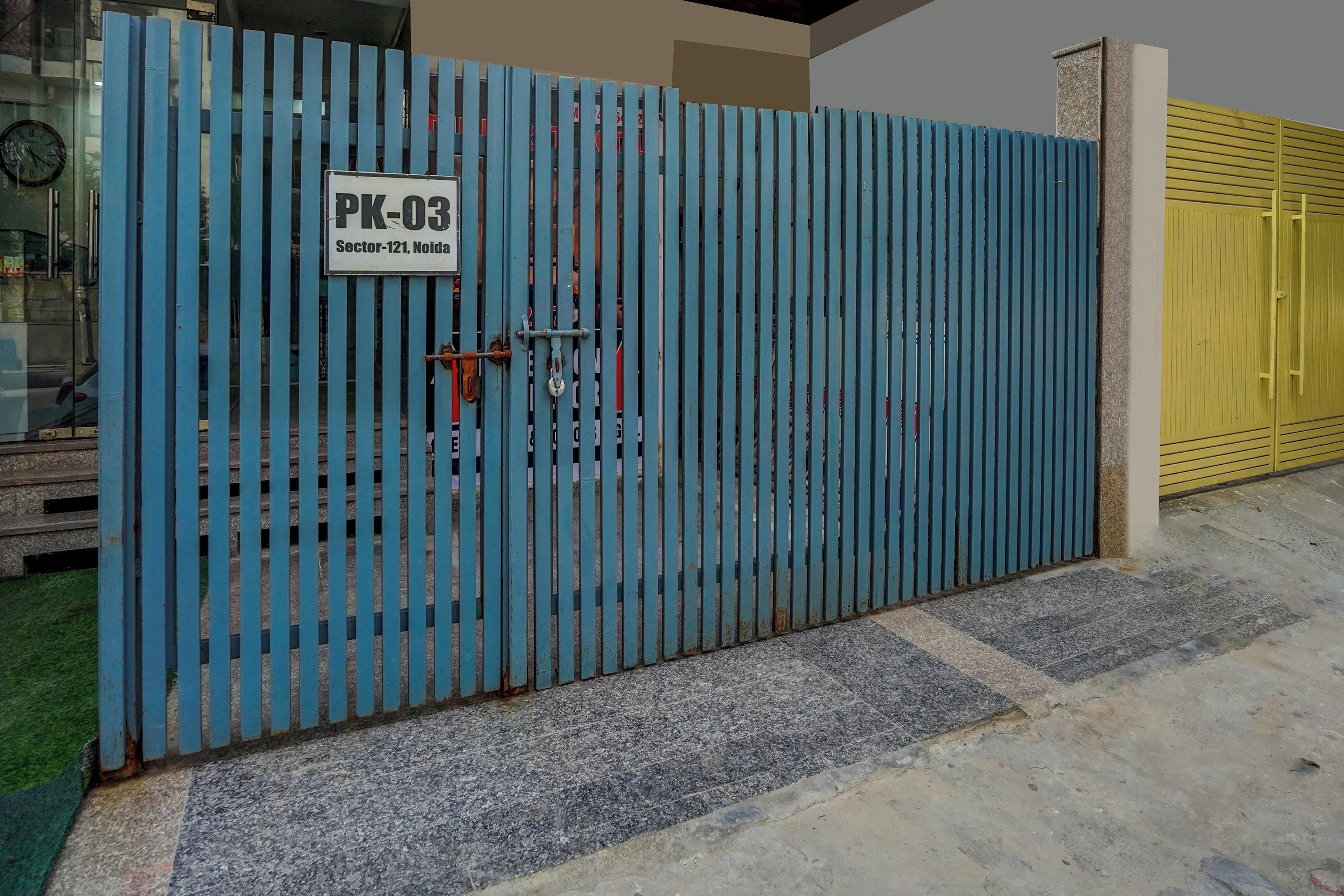 Un cancello di metallo blu con un cartello che riporta 'PK-03 Sector-121 Noida'.