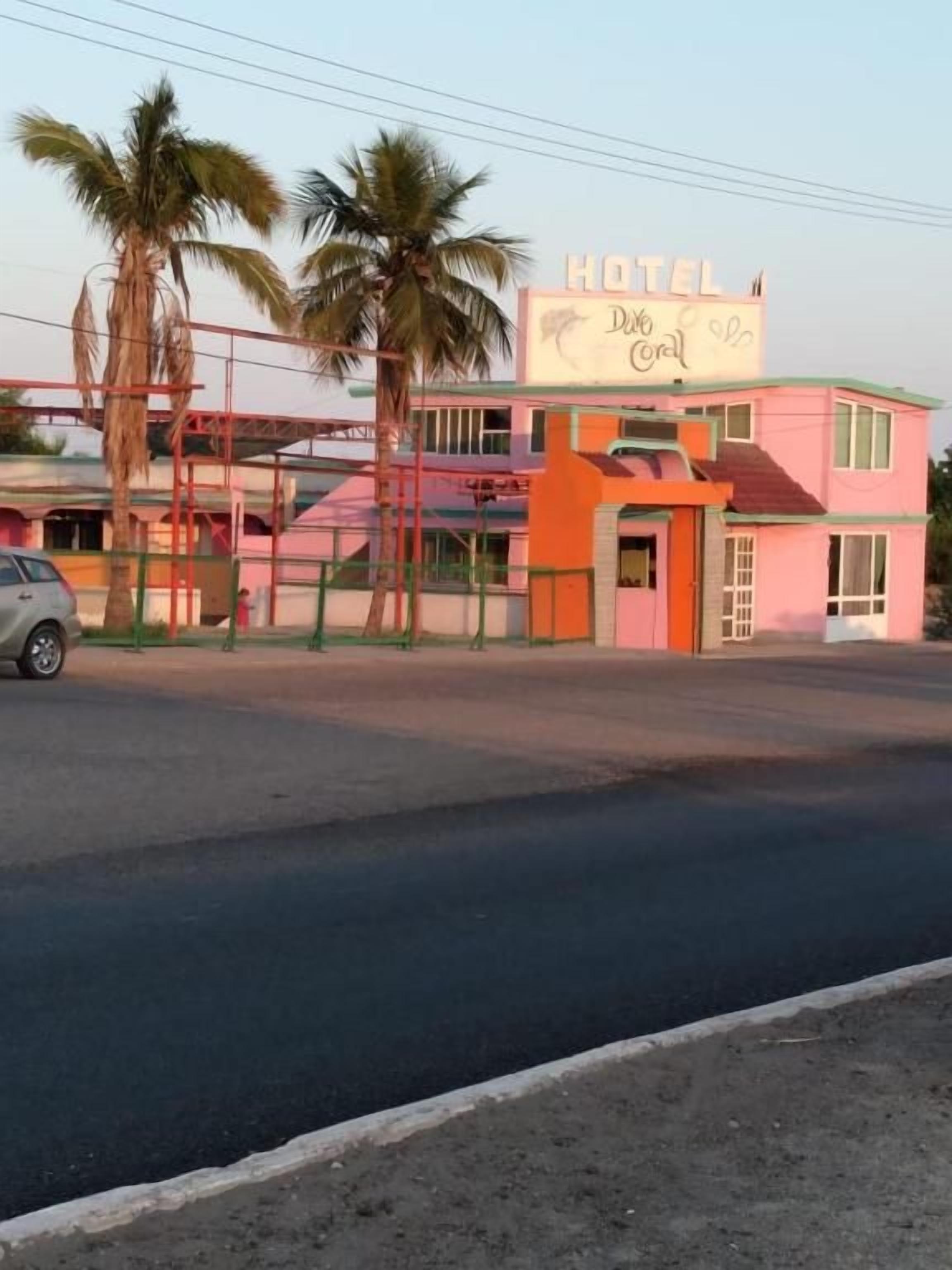 A pink building with a sign that reads 'HOTEL' and 'Del Coral.'
